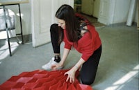 a woman is laying down on the floor with a red piece of paper